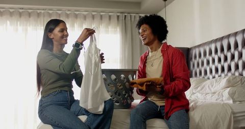 Happy Couple Folding Laundry Near Basket in Modern Bedroom