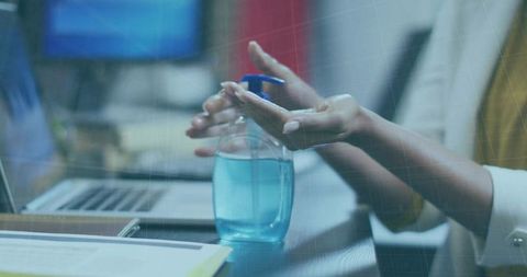 Office hands sanitizing at desk with laptop in contemporary workspace