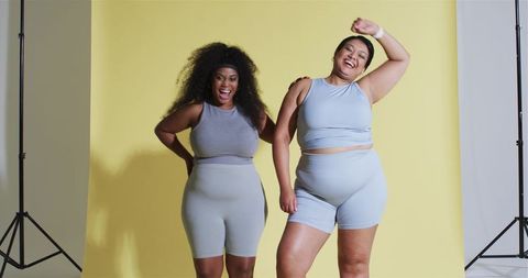 Diverse friends laughing in activewear against yellow backdrop