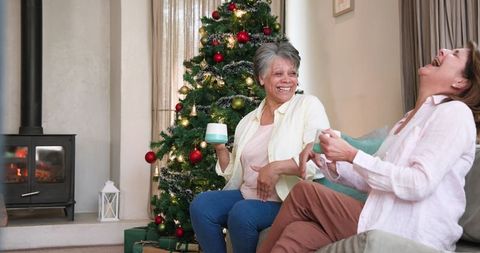 Joyful Mother and Daughter Chatting by Christmas Tree at Home