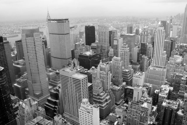 A monochrome aerial view of an urban landscape featuring closely packed skyscrapers and high-rise buildings, capturing the bustling atmosphere of a major city. Ideal for use in projects related to urban life, architecture, real estate marketing, and illustrating metropolitan environments.