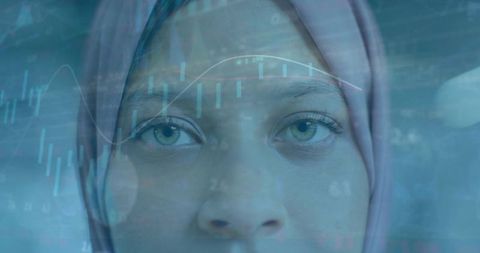 Young muslim woman in hijab analyzing financial data with digital charts overlay closeup