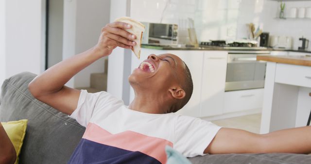 Joyful Boy Eating Sandwich on Couch in Modern Kitchen - Download Free Stock Images Pikwizard.com