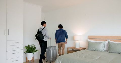 Two men packing suitcase in bedroom for travel adventure