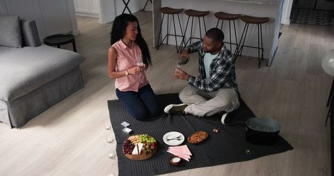 Couple Enjoying Indoor Picnic with Champagne and Snacks