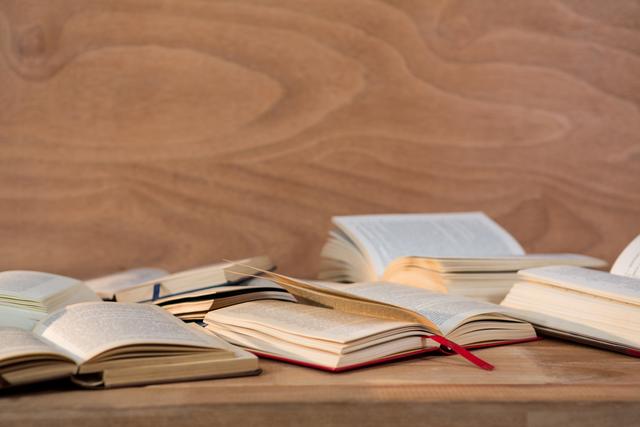 Various open books spread across a wooden table, ideal for themes related to studying, literature, education, libraries, and acquiring knowledge. Can be used in educational articles, blog posts about reading habits, or to promote academic resources.