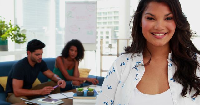 Smiling Woman in Office with Colleagues Discussing Work in Background - Download Free Stock Images Pikwizard.com