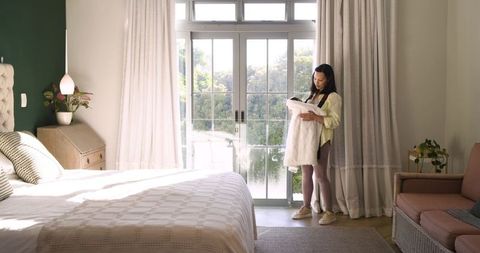 Mother Gently Cradling Infant in Sunlit Bedroom