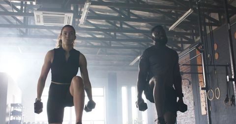 Diverse athletes lunging with dumbbells in modern gym