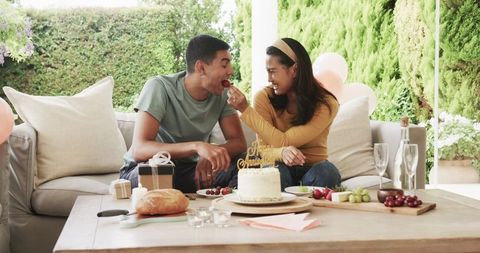 Young Couple Celebrating Birthday Outdoors with Cake and Laughter