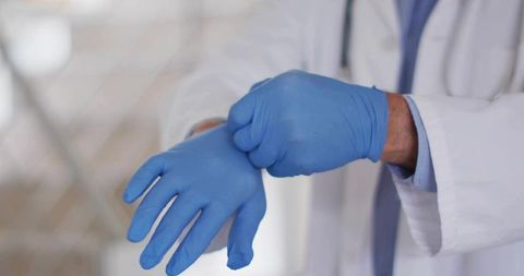 Senior Doctor Wearing Protective Gloves in Medical Office