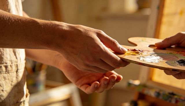 Passing Painter Palette Between Artists in Sunlit Studio Close-up Hands Sharing Color