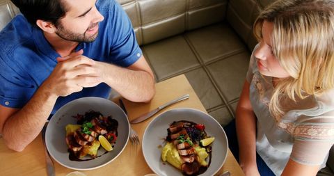 Young Couple Enjoying Meal and Conversation at Restaurant