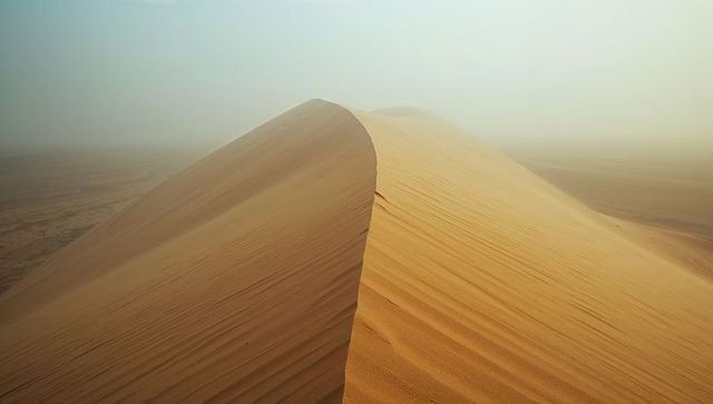 Majestic Sand Dune With Sharp Ridge in Hazy Desert Setting