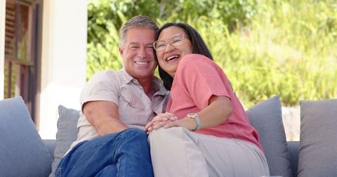 Smiling Diverse Couple Relaxing on Tranquil Porch Sofa
