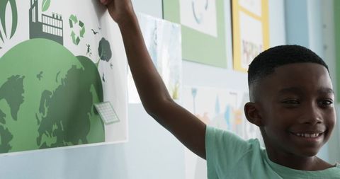 Smiling black teen boy displaying environmental poster promoting recycling and sustainability