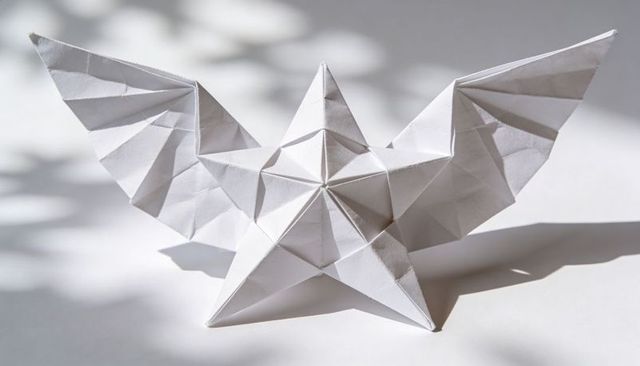 Origami star with angular wings casting soft shadows on white minimal tabletop