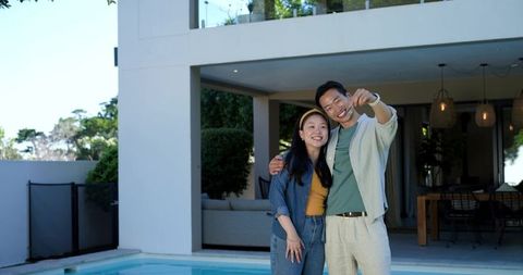 Asian couple taking selfie by pool at modern home relaxed backyard romance