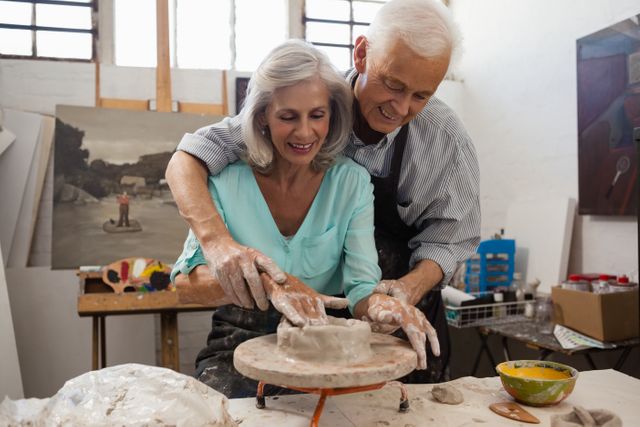 Smiling senior man assisting senior woman in making pottery during drawing class