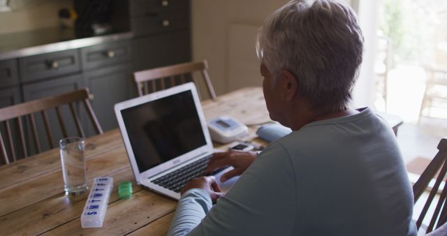 Senior Woman Typing on Laptop at Wooden Table in Kitchen - Download Free Stock Images Pikwizard.com