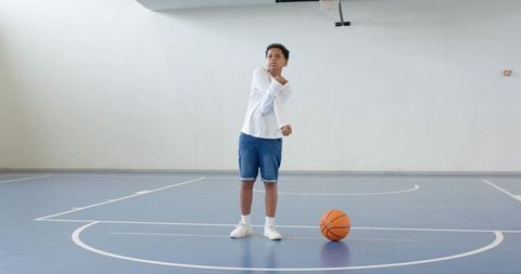 Youth stretching in indoor basketball court with ball