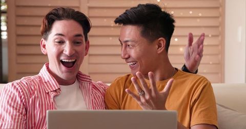 Happy Diverse Male Couple Enjoying Together on Laptop at Home
