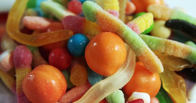 Vivid, assorted gummy and sour candies assortment close-up, featuring bright colors and sugar coating. Use for colorful advertisements, children's parties, or confectionery promotions. The vibrant variety of textures and shapes add a playful and appetizing element.