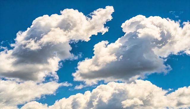 Drifting sunlit cumulus clouds over vivid blue sky for tranquil nature background and design
