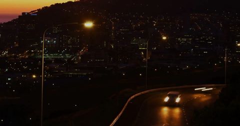 Night Drive on Winding Road with Glowing City Lights in Background - Download Free Stock Images Pikwizard.com