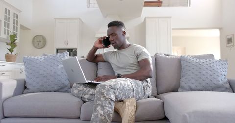 African American Soldier Multitasking with Laptop and Smartphone at Home