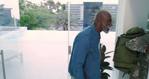 Happy senior father welcoming son in military uniform home
