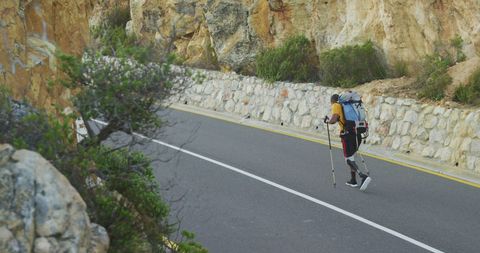 Man with Prosthetic Leg Hiking Mountain Road with Backpack