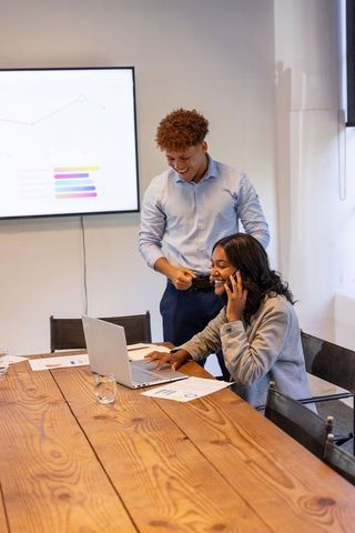 Diverse team collaborating over laptop and phone during meeting with charts