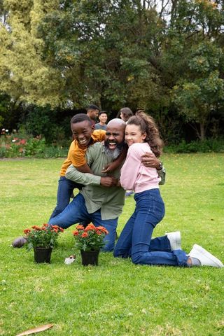 Family Bonding Moment in Park with Potted Red Flowers