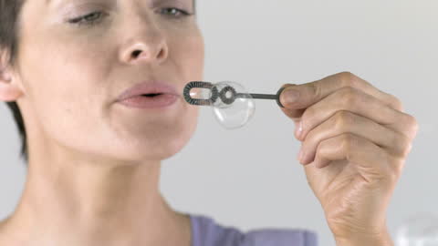Woman Gently Blowing Bubbles in Slow Motion