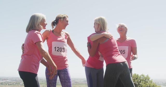 Senior women in pink shirts finishing marathon, celebrating together, showing unity and fitness success. Useful for promoting active lifestyle in older adults, teamwork, community events, health and fitness campaigns.
