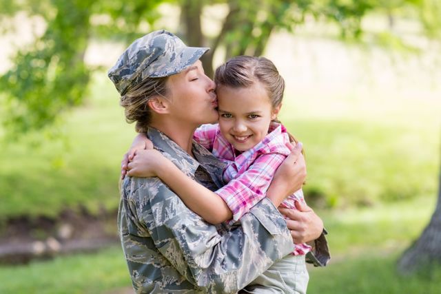 Happy female soldier kissing her daughter in park - Download Free Stock Photos Pikwizard.com