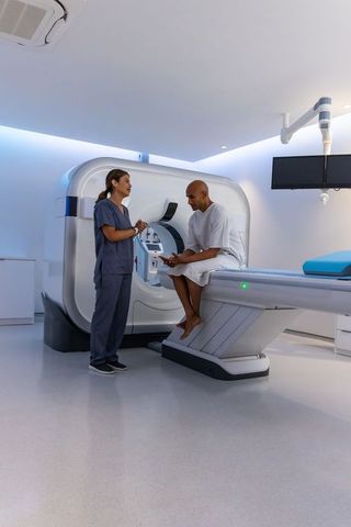 African american patient consulting with radiology technologist beside ct scanner