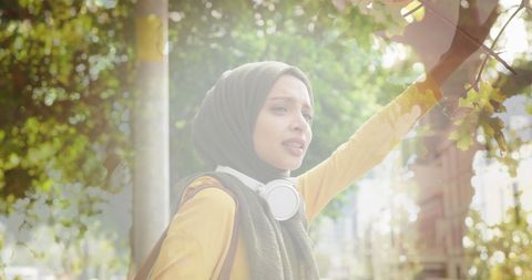 Woman in Hijab Flagging Down Taxi in Urban Environment