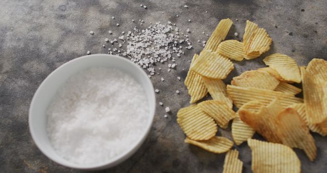 Close up of potato chips and bowl of salt on black surface - Download Free Stock Photos Pikwizard.com