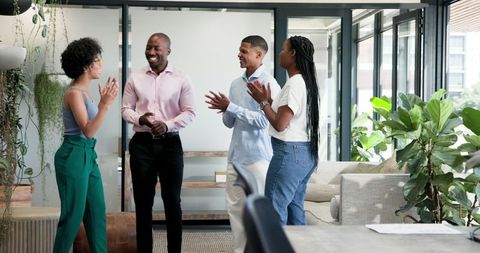 Diverse colleagues celebrating in modern office space