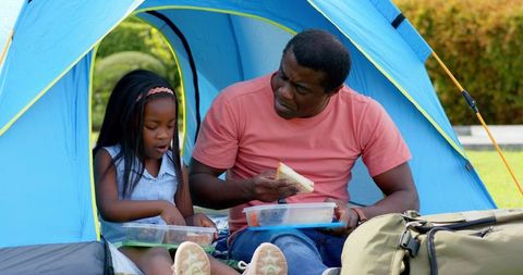 Father and Daughter Enjoying Lunch Inside Tent in Backyard
