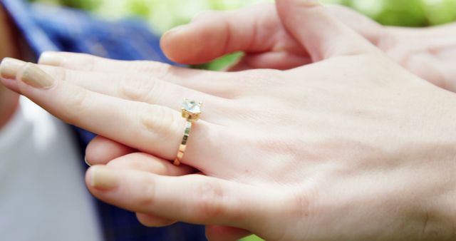 A close-up shows a Caucasian woman's hand adorned with a new engagement ring, with copy space. The focus on the ring suggests a recent proposal or engagement celebration.