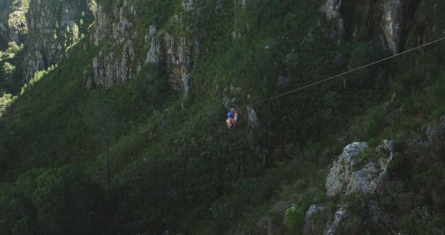 Caucasian woman ziplining with safety belts in mountains, copy space. Ziplining, active lifestyle, safety and nature concept, unaltered.
