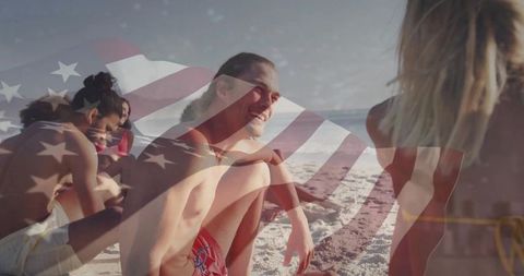 Smiling man in red swim trunks sitting with friends on beach with American flag overlay