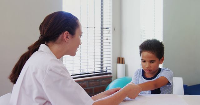 Therapist in white coat assisting young boy with exercises during physical therapy session. Ideal for use in healthcare, rehabilitation, and child development contexts, or to illustrate medical services and treatments for children.