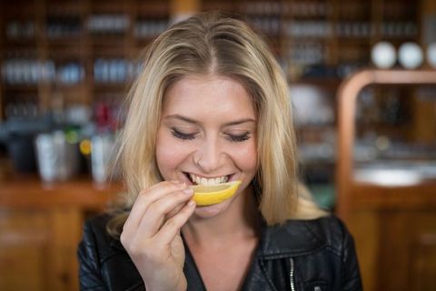 Young Woman Enjoying Lemon Slice in Stylish Bar Setting - Download Free Stock Images Pikwizard.com