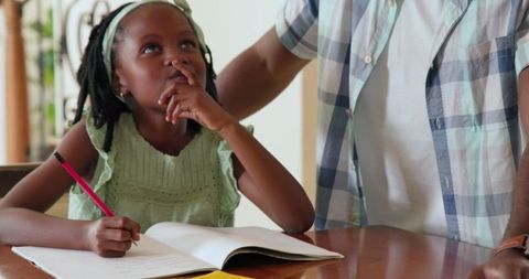 Father Helping Daughter with Homework at Table on Sunny Day