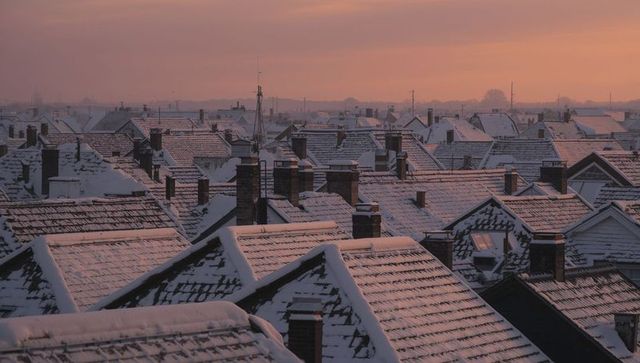Snow-blanketing terraced rooftops forming repeating gables and chimneys at sunrise with pastel sky