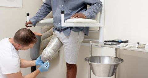Prosthetist adjusting metallic leg in medical clinic
